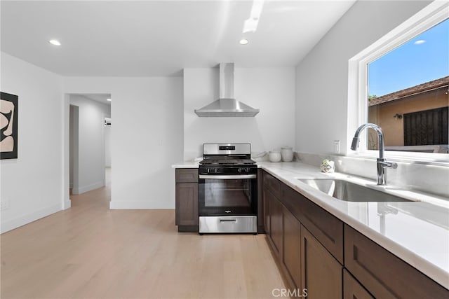 1005 E Cruces St, Wilmington, CA 90744 - kitchen with wall chimney exhaust hood, gas range, a sink, light wood-style flooring, and dark brown cabinets