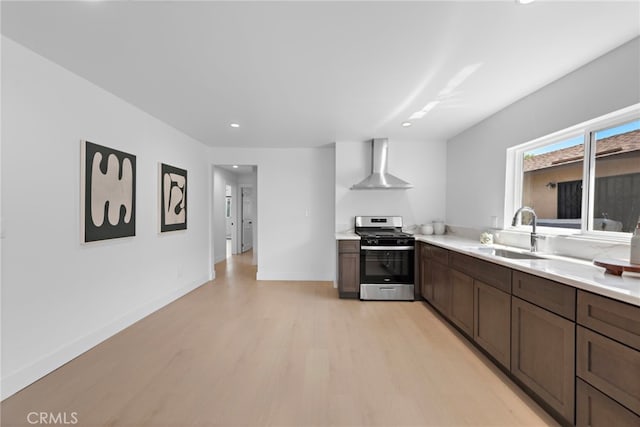 1005 E Cruces St, Wilmington, CA 90744 - kitchen featuring stainless steel range with gas stovetop, wall chimney range hood, a sink, light wood-style floors, and light countertops