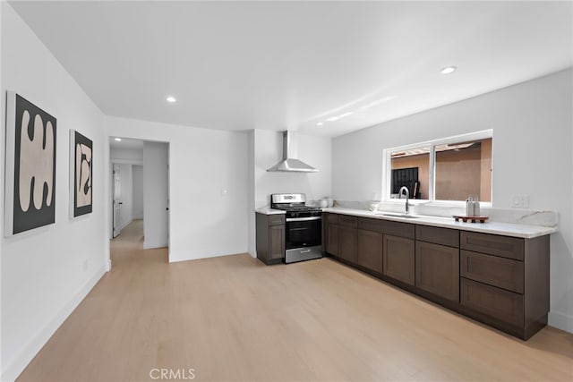 1005 E Cruces St, Wilmington, CA 90744 - kitchen with gas stove, wall chimney range hood, a sink, light wood-style flooring, and light countertops