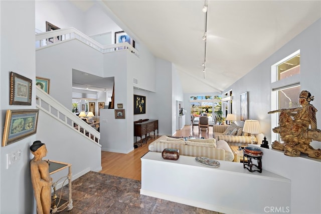 30252 Sonrisa Ln, Laguna Niguel, CA 92677 - living area with rail lighting, high vaulted ceiling, stairway, baseboards, and dark stone finish flooring