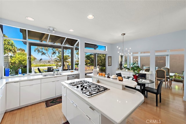 30252 Sonrisa Ln, Laguna Niguel, CA 92677 - kitchen featuring stainless steel gas cooktop, light countertops, light wood-style flooring, white cabinets, and a center island