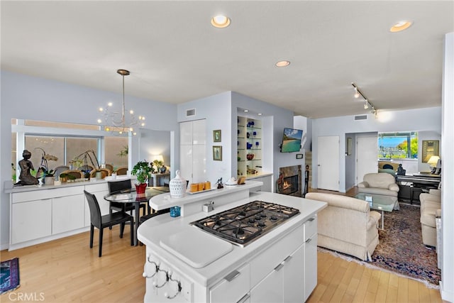 30252 Sonrisa Ln, Laguna Niguel, CA 92677 - kitchen with stainless steel gas stovetop, light wood-style flooring, a chandelier, white cabinets, and recessed lighting