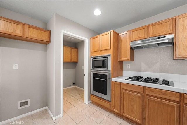 3057 Kilt Ct, Lancaster, CA 93535 - kitchen featuring appliances with stainless steel finishes, under cabinet range hood, tile counters, light tile patterned flooring, and baseboards