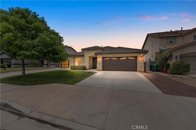 3057 Kilt Ct, Lancaster, CA 93535 - mediterranean / spanish-style house with an attached garage, driveway, stucco siding, a tiled roof, and a front yard