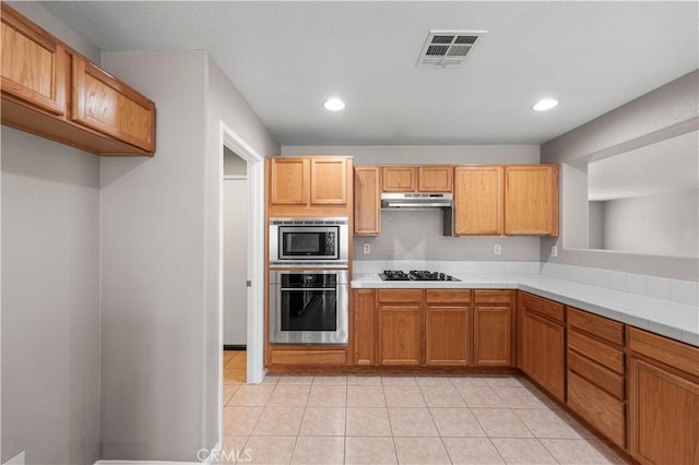 3057 Kilt Ct, Lancaster, CA 93535 - kitchen with appliances with stainless steel finishes, under cabinet range hood, recessed lighting, light tile patterned floors, and tile countertops