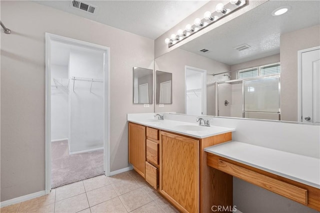 3057 Kilt Ct, Lancaster, CA 93535 - full bath featuring double vanity, a shower with door, a walk in closet, baseboards, and tile patterned flooring