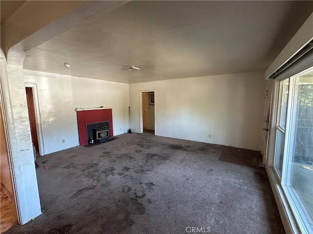 2233 Marguerite St, Dos Palos, CA 93620 - unfurnished living room featuring carpet flooring and a wood stove