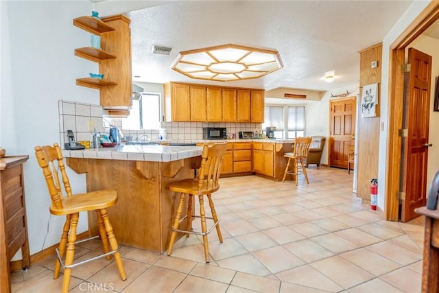 5131 Cygnet Rd A-B, Unit A-B Phelan, CA 92371 - kitchen with a peninsula, tile countertops, black microwave, tasteful backsplash, and plenty of natural light