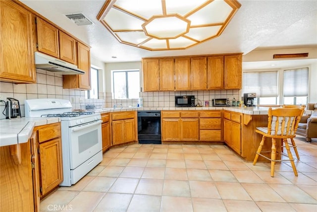 5131 Cygnet Rd A-B, Unit A-B Phelan, CA 92371 - kitchen featuring black appliances, under cabinet range hood, tile counters, a peninsula, and decorative backsplash