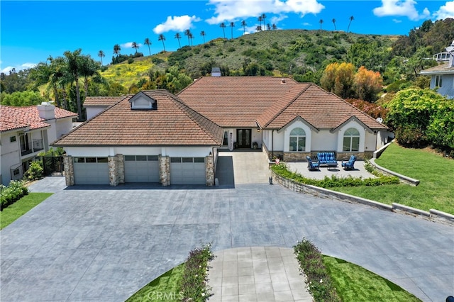 30927 Steeplechase Dr, San Juan Capistrano, CA 92675 - view of front of home featuring stone siding, a garage, driveway, stucco siding, and a tile roof