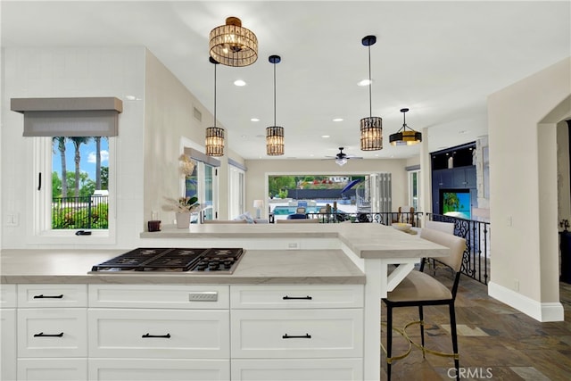 30927 Steeplechase Dr, San Juan Capistrano, CA 92675 - kitchen featuring stainless steel gas stovetop, a peninsula, white cabinets, dark stone finish floors, and recessed lighting