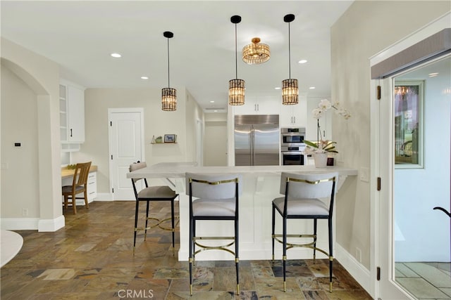 30927 Steeplechase Dr, San Juan Capistrano, CA 92675 - kitchen featuring appliances with stainless steel finishes, a peninsula, white cabinets, a kitchen bar, and recessed lighting