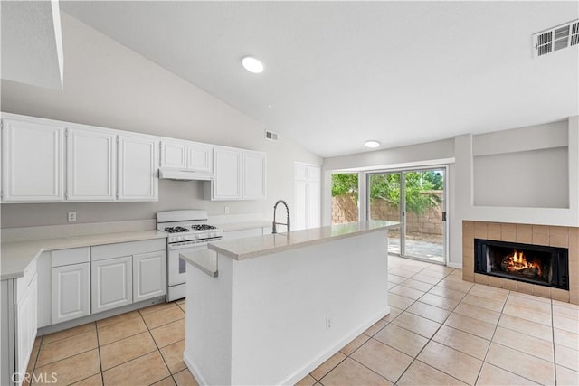 2101 Thomas Dr, Lancaster, CA 93535 - kitchen with white gas range, lofted ceiling, white cabinets, light tile patterned floors, and under cabinet range hood