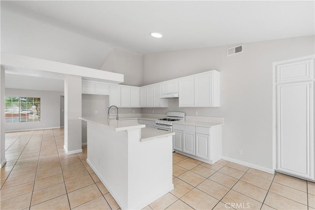 2101 Thomas Dr, Lancaster, CA 93535 - kitchen featuring light tile patterned floors, light countertops, under cabinet range hood, white range with gas stovetop, and a center island with sink
