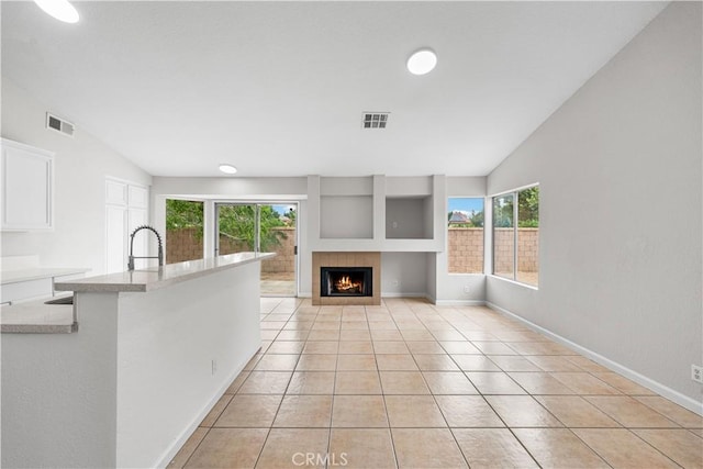 2101 Thomas Dr, Lancaster, CA 93535 - unfurnished living room with vaulted ceiling, a tile fireplace, light tile patterned flooring, and baseboards