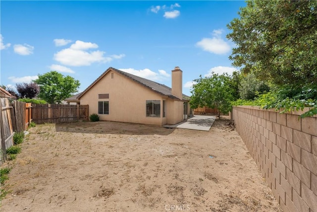 2101 Thomas Dr, Lancaster, CA 93535 - back of property featuring a fenced backyard, a chimney, stucco siding, and a patio
