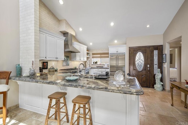 1744 Tattenham Rd, Encinitas, CA 92024 - kitchen with built in fridge, wall chimney range hood, stone tile flooring, a sink, and lofted ceiling