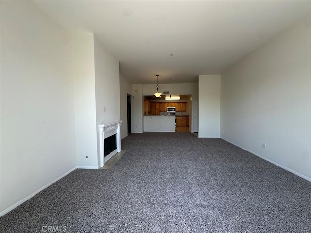 7551 Jordan Ave Unit 410, Canoga Park, CA 91303 - unfurnished living room featuring dark colored carpet, baseboards, and a fireplace with flush hearth
