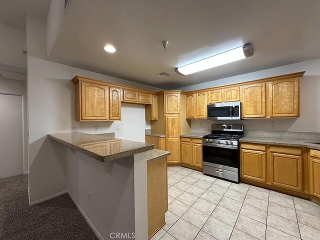 7551 Jordan Ave Unit 410, Canoga Park, CA 91303 - kitchen featuring stainless steel appliances, a peninsula, a breakfast bar area, light tile patterned floors, and recessed lighting