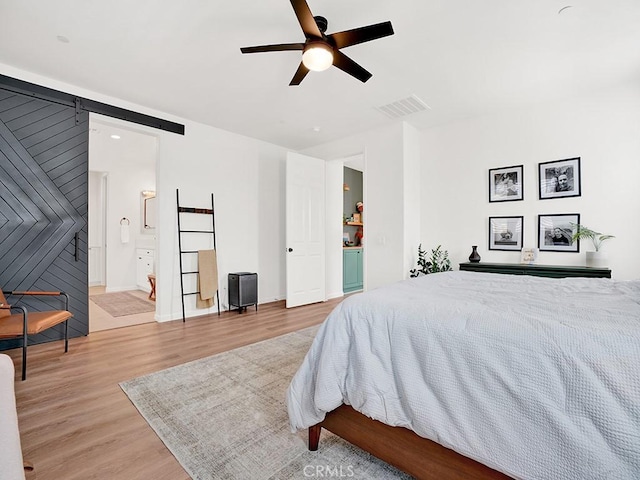 8967 Sunshine Valley Way, Corona, CA 92883 - bedroom with wood finished floors, a barn door, ceiling fan, baseboards, and ensuite bathroom