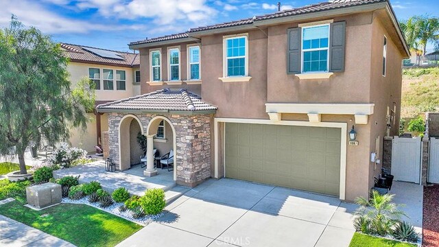 8967 Sunshine Valley Way, Corona, CA 92883 - mediterranean / spanish-style home with a tiled roof, stucco siding, concrete driveway, a garage, and covered porch