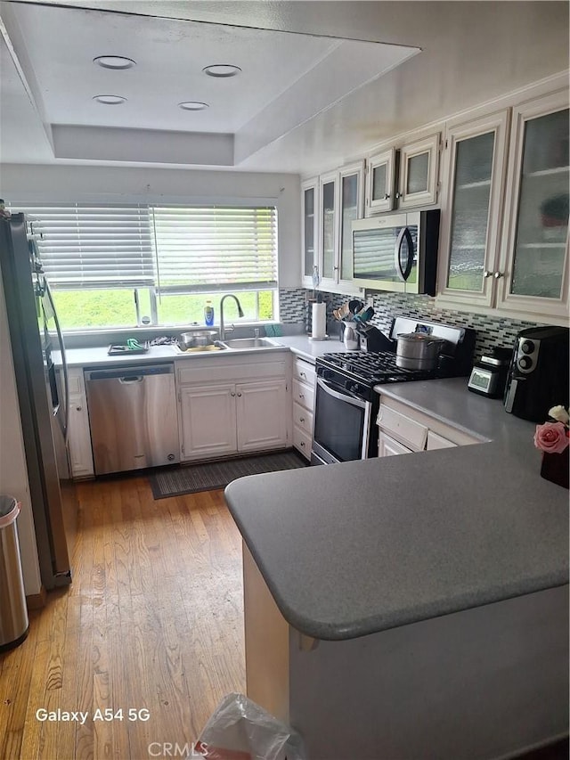 10605 Cordoba Ct, Whittier, CA 90601 - kitchen with appliances with stainless steel finishes, a raised ceiling, a sink, a peninsula, and light wood finished floors