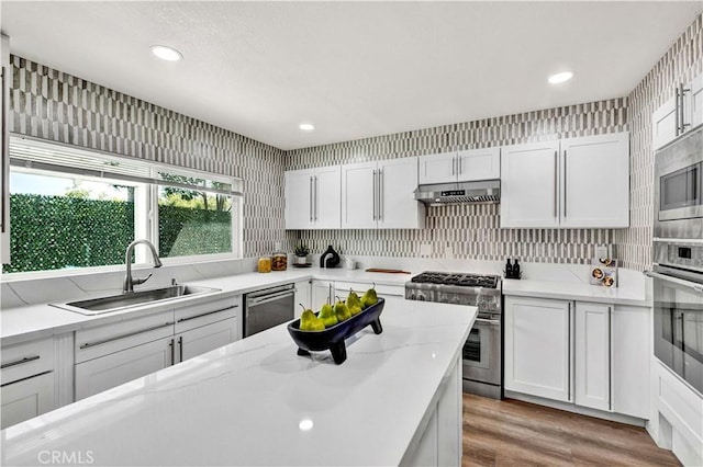 921 Dahlia Ave, Costa Mesa, CA 92626 - kitchen with stainless steel appliances, a sink, under cabinet range hood, wood finished floors, and white cabinetry