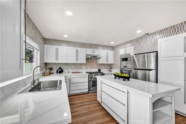 921 Dahlia Ave, Costa Mesa, CA 92626 - kitchen with appliances with stainless steel finishes, under cabinet range hood, a sink, wallpapered walls, and light countertops