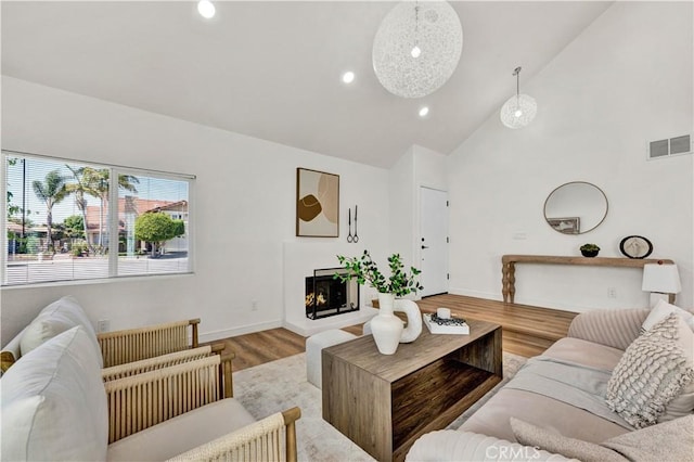 921 Dahlia Ave, Costa Mesa, CA 92626 - living room with recessed lighting, wood finished floors, baseboards, a warm lit fireplace, and high vaulted ceiling