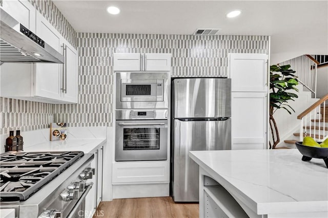 921 Dahlia Ave, Costa Mesa, CA 92626 - kitchen with appliances with stainless steel finishes, exhaust hood, light stone counters, white cabinetry, and recessed lighting