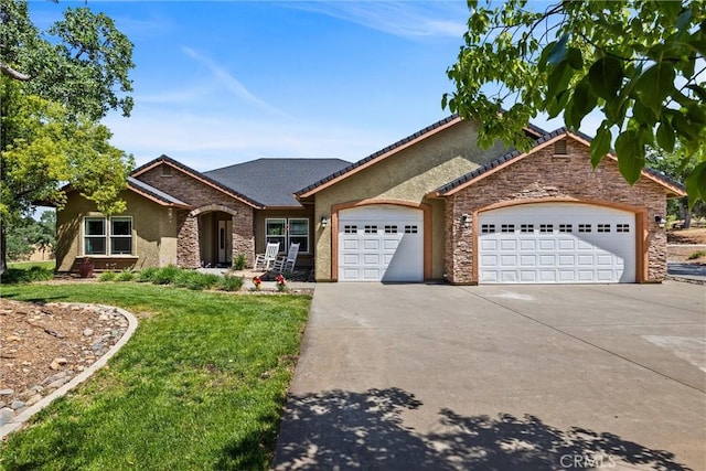 14690 Paynes Creek Rd, Red Bluff, CA 96080 - view of front of house featuring stone siding, driveway, stucco siding, an attached garage, and a front yard