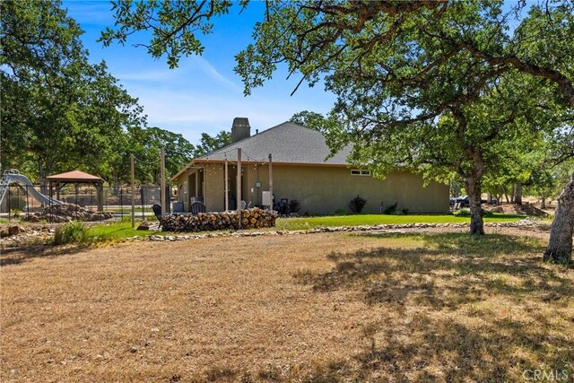 14690 Paynes Creek Rd, Red Bluff, CA 96080 - view of property exterior featuring a gazebo, a yard, a chimney, and stucco siding