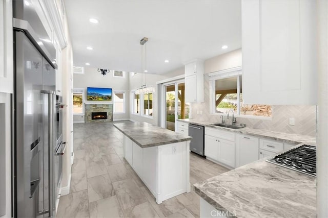 5420 Kodiak Mountain Dr, Yorba Linda, CA 92887 - kitchen with stainless steel appliances, a kitchen island, open floor plan, light stone countertops, and a warm lit fireplace