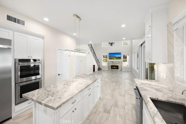 5420 Kodiak Mountain Dr, Yorba Linda, CA 92887 - kitchen featuring stainless steel appliances, open floor plan, a sink, white cabinetry, and light stone countertops