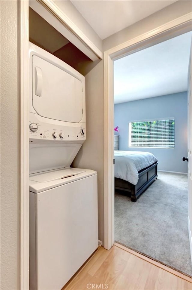 20122 Bayfront Ln Unit 102, Huntington Beach, CA 92646 - washroom with stacked washing machine and dryer and light wood finished floors