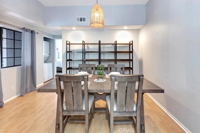20122 Bayfront Ln Unit 102, Huntington Beach, CA 92646 - dining area featuring stacked washing machine and dryer, wood finished floors, and baseboards