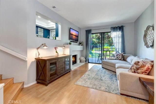 20122 Bayfront Ln Unit 102, Huntington Beach, CA 92646 - living area featuring wood finished floors, stairs, a warm lit fireplace, and baseboards