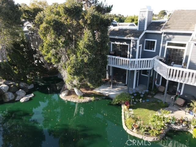 20122 Bayfront Ln Unit 102, Huntington Beach, CA 92646 - rear view of property with a deck, a patio area, a small pond, and a chimney