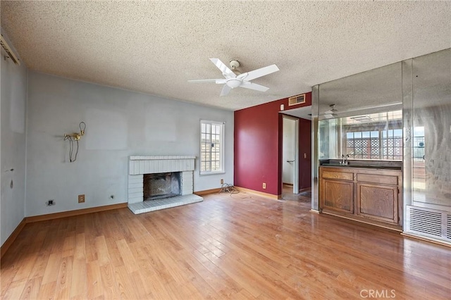 1945 Cumberland Dr, West Covina, CA 91792 - unfurnished living room featuring a textured ceiling, ceiling fan, a fireplace, light wood finished floors, and baseboards