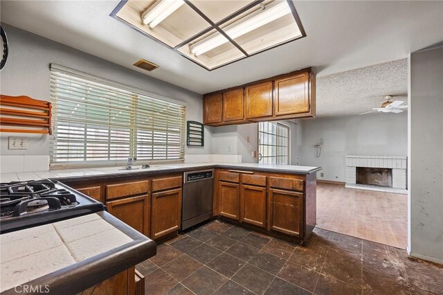 1945 Cumberland Dr, West Covina, CA 91792 - kitchen with stainless steel dishwasher, a peninsula, a sink, a fireplace, and brown cabinets