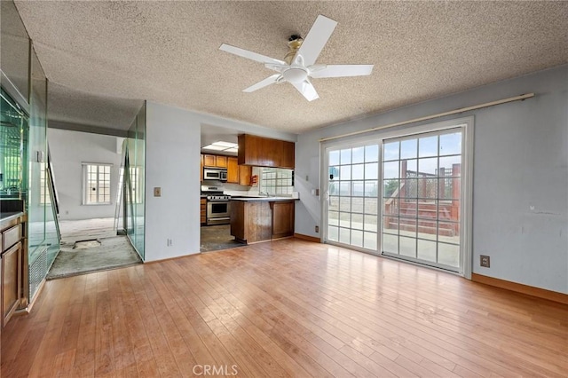 1945 Cumberland Dr, West Covina, CA 91792 - kitchen featuring stainless steel appliances, brown cabinets, open floor plan, a textured ceiling, and light wood-type flooring