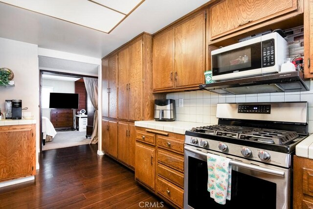 4734 E Tanglewood Ave, Anaheim, CA 92807 - kitchen with gas stove, tile counters, extractor fan, brown cabinetry, and dark wood-style floors