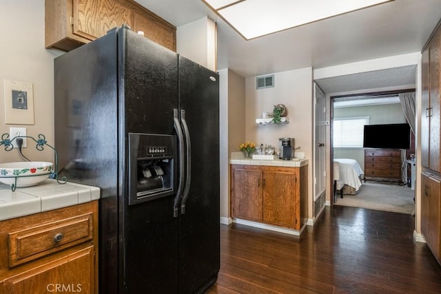 4734 E Tanglewood Ave, Anaheim, CA 92807 - kitchen featuring black refrigerator with ice dispenser, tile counters, dark wood finished floors, brown cabinetry, and baseboards