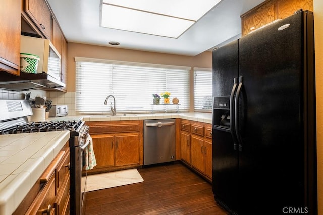 4734 E Tanglewood Ave, Anaheim, CA 92807 - kitchen with appliances with stainless steel finishes, tile countertops, a sink, brown cabinets, and dark wood-type flooring