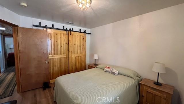 33477 Fern Dr, Green Valley Lake, CA 92341 - bedroom with wood finished floors and a barn door