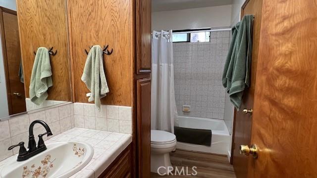 33477 Fern Dr, Green Valley Lake, CA 92341 - full bath with vanity, toilet, shower / bath combo with shower curtain, backsplash, and wood finished floors