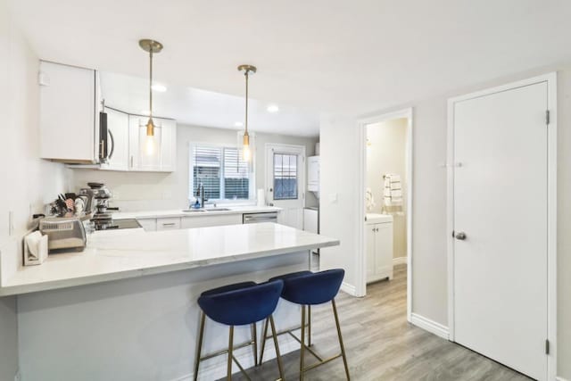 951 Amistad Ct Unit C, El Cajon, CA 92019 - kitchen featuring a sink, a peninsula, white cabinets, light wood finished floors, and hanging light fixtures