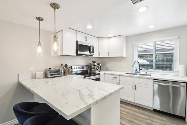 951 Amistad Ct Unit C, El Cajon, CA 92019 - kitchen featuring appliances with stainless steel finishes, a sink, a peninsula, light stone countertops, and white cabinets