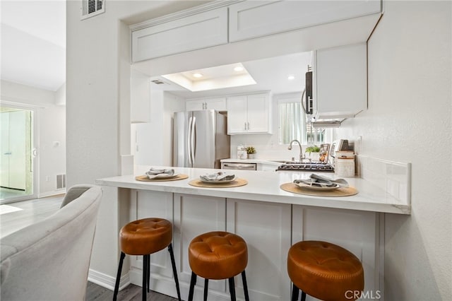 28241 Sorrento Unit 124, Laguna Niguel, CA 92677 - kitchen with freestanding refrigerator, a peninsula, light countertops, white cabinets, and wood finished floors