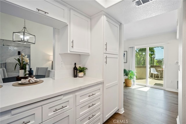 28241 Sorrento Unit 124, Laguna Niguel, CA 92677 - kitchen featuring light countertops, white cabinets, dark wood finished floors, a chandelier, and decorative light fixtures
